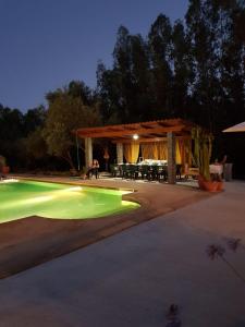 una piscina con luces verdes en un patio trasero por la noche en Villa Gambula, en Carbonia
