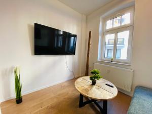 ein Wohnzimmer mit einem Tisch und einem TV an der Wand in der Unterkunft Charming Apartments l 7 Beds l 4 Bedrooms l WI-FI in Geseke