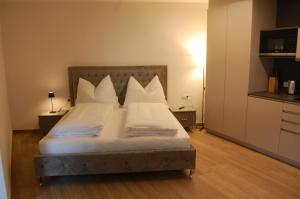 - une chambre avec un lit doté de draps et d'oreillers blancs dans l'établissement myQuartier - Central City DeLuxe Apartments, à Innsbruck