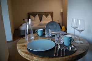 a table with plates and wine glasses and a bed at myQuartier - Central City DeLuxe Apartments in Innsbruck