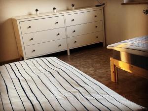 a bedroom with a dresser and a bed with a striped mattress at Simsongarage Mönchswalde in Obergurig