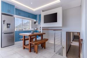Hermanus的住宿－Your Cozy Haven in Chanteclaire，厨房配有蓝色橱柜和木桌