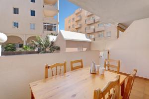 een houten tafel en stoelen op een balkon met gebouwen bij Apartamento El Médano Marineda in Granadilla de Abona