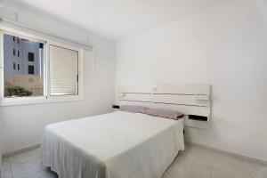 een witte slaapkamer met een bed en een raam bij Apartamento El Médano Marineda in Granadilla de Abona +17 foto's