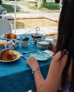 a woman sitting at a blue table with food on it at Relais Corte Degli Aragonesi in Ischia