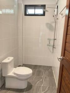 een witte badkamer met een toilet en een douche bij Nuree Villa in Phra Ae beach