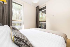 um quarto com uma cama branca e uma janela em Pine Forest View Apt With Balcony, By Cohost em Palanga