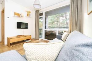 uma sala de estar com um sofá e uma televisão em Pine Forest View Apt With Balcony, By Cohost em Palanga