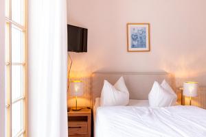 een slaapkamer met een bed met witte lakens en een televisie bij Strandhaus Claassen 06 in Ahrenshoop