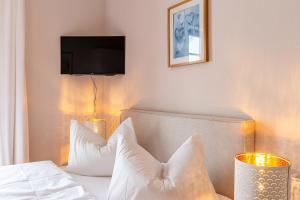 een slaapkamer met een bed met witte kussens en een televisie bij Strandhaus Claassen 06 in Ahrenshoop