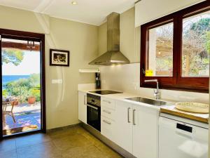 a kitchen with white cabinets and a sink and a window at Maset CostaBravaSi in Sant Feliu de Guixols