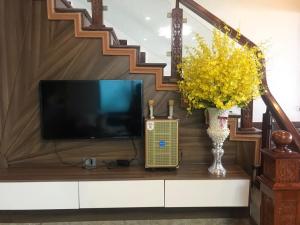 a living room with a television and a vase of yellow flowers at Hiệp Gà Villa Tam Đảo - Venuestay in Tam Ðảo