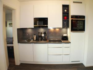 a kitchen with white cabinets and a sink at Sielhuus 10 in Fedderwarderdeich