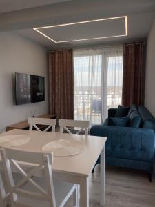 een woonkamer met een blauwe bank en een tafel bij Noah Apartment Self Check-in Otopeni in Otopeni
