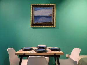 een tafel met stoelen en een schilderij aan een groene muur bij "On the beach" Glamour Sunrise Apartment in Durrës +17 foto's