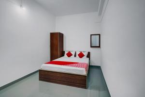Bett mit roten Kissen in einem weißen Zimmer in der Unterkunft Super OYO Flagship The Mahalaxmi Inn in Dibrugarh