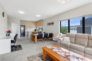 a living room with a couch and a table at Sleek Vista Townhouse with deck and air-con in Auckland