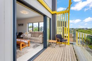 a balcony with a couch and a table on a deck at Sleek Vista Townhouse with deck and air-con in Auckland