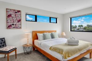 a bedroom with a bed and two windows at Sleek Vista Townhouse with deck and air-con in Auckland