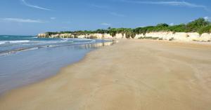una playa de arena con el océano y las rocas en Villa Aurea, en Ispica