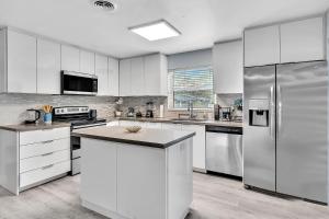 a kitchen with white cabinets and a stainless steel refrigerator at Hard Rock Hotel & Casino Getaway 3 Bdrm Villa in Fort Lauderdale