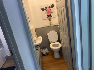 a bathroom with a toilet and a cow painting on the wall at Brays View in Ely