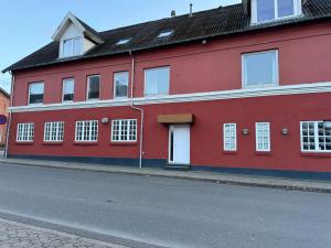 un edificio rosso sul lato di una strada di aday - 4 bedrooms holiday apartment in Bronderslev a Brønderslev