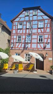 Külsheim的住宿－Brunnenputzer Pension Restaurant，一组椅子和遮阳伞在建筑前