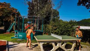 deux jeunes hommes debout autour d'une table de ping-pong dans l'établissement CAMPING PLEIN SOLEIL, à Lourdes