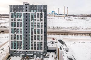 een hoog wit gebouw met sneeuw op de grond bij Однокомнатная для 4 гостей недалеко от аэропорта in Astana