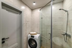 a washing machine in a bathroom with a shower at Однокомнатная для 4 гостей недалеко от аэропорта in Astana