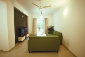 a living room with a green couch and a television at Asta by Avim in Goa