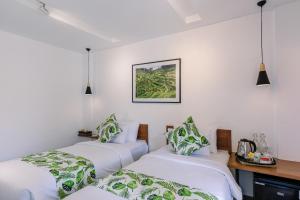 3 camas en una habitación con paredes blancas en Chandi Hotel Ubud en Ubud
