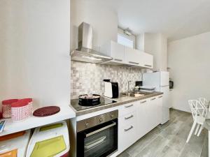 uma cozinha com armários brancos e um forno com placa de fogão em La Corte di Nonna Ada em Pianillo