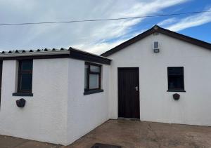 a white house with a black door and windows at Stay-A-While by Ustay in Saldanha