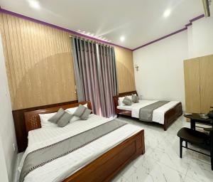 a hotel room with two beds and a desk at Minh Hoàng Hotel - Phan Thiết in Ấp Bình Hưng