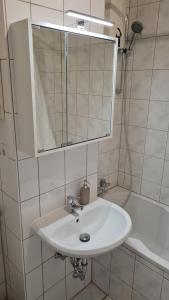 La salle de bains est pourvue d'un lavabo, d'un miroir et d'une baignoire. dans l'établissement unique: cozy - balcony - kitchen - netflix, à Brême