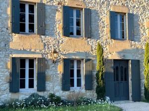 Saint-Seurin-de-Prats的住宿－Domaine des Monges，上面有蓝色百叶窗的建筑