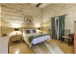 - une chambre avec un grand lit et un mur en pierre dans l'établissement Authentic 4 Br Gozitan Farmhouse with Private Pool by 360 Estates, à L-Għarb