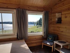 ein Schlafzimmer mit zwei Fenstern und einem Bett und einem Stuhl in der Unterkunft North Lake Villa Rooms in Plateliai
