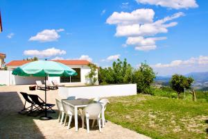 einen Tisch und Stühle mit Sonnenschirm auf dem Rasen in der Unterkunft Batoca by Burra Velha - Private House in Celorico de Basto