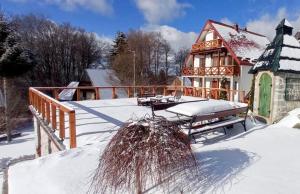 a house with a deck in the snow at Apartmani Vujanac in Kopaonik