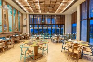a restaurant with tables and chairs and windows at TTC Van Phong Bay Resort - Himalaya Sauna & Steam Retreat Included in Ninh Hòa