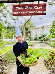 a boy wearing a chef hat holding a basket of vegetables at TTC Van Phong Bay Resort - Himalaya Sauna & Steam Retreat Included in Ninh Hòa