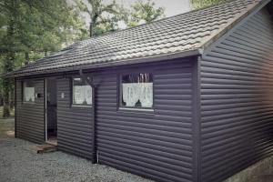 un grand garage noir avec deux fenêtres et un toit dans l'établissement Chalet nature au cœur des Ardennes, à Somme-Leuze