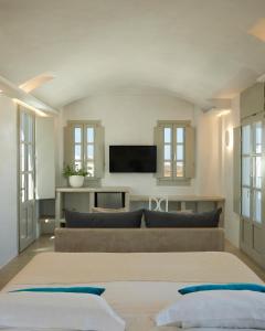 a living room with a couch and a flat screen tv at Danae Suites Santorini in Oia