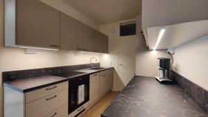 a kitchen with white cabinets and a black counter top at Green Getaway - near Helsinki Vantaa Airport, top-floor, free parking & wifi in Vantaa