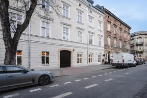 a car parked on a street next to a white building at MameHome Apartments in Krakow