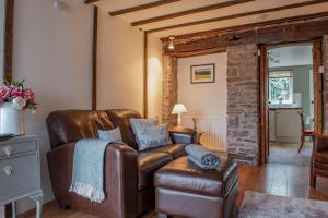 a living room with a leather couch and a chair at Central Brecon, Pretty Victorian Cottage in Brecon
