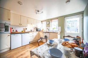 una cocina con armarios blancos y una mesa con comida. en Central Brecon, Pretty Victorian Cottage, en Brecon